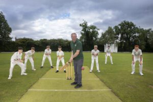 Rob Jones from Lock Stock readies to strike a ball at a cricket crease.